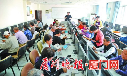 厦门老年大学电脑教室里,老人们对着电脑上的手机操作认真学。