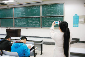 一位大学生下课后正在拍摄课堂板书