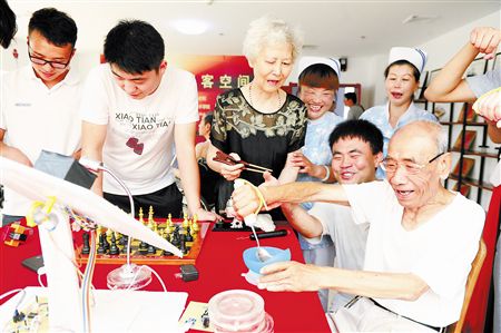 老人在体验助老餐具。本报记者