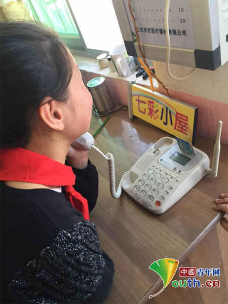 图为一位小女孩与在外打工的父亲通电话。周海渊供图 图为一位小女孩与在外打工的父亲通电话。周海渊供图